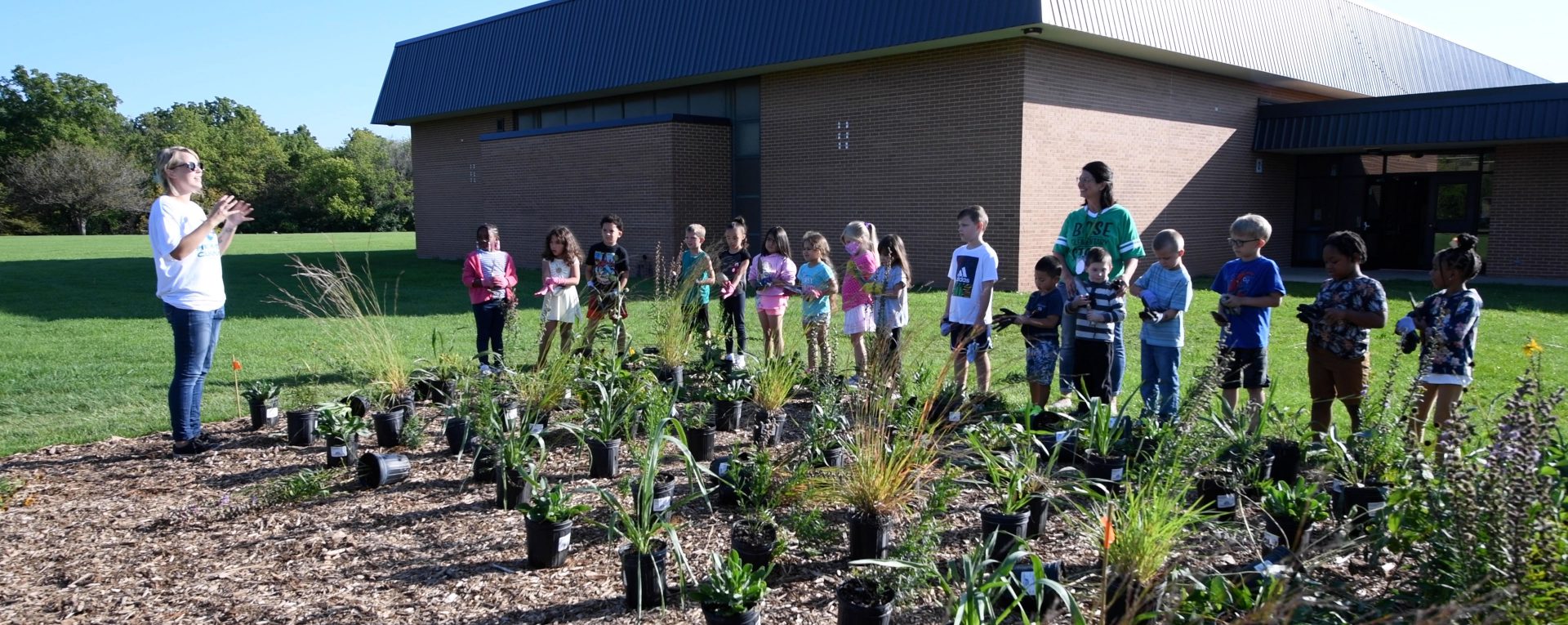 A group of students gathered around the garden outside the Bose Elementary building.