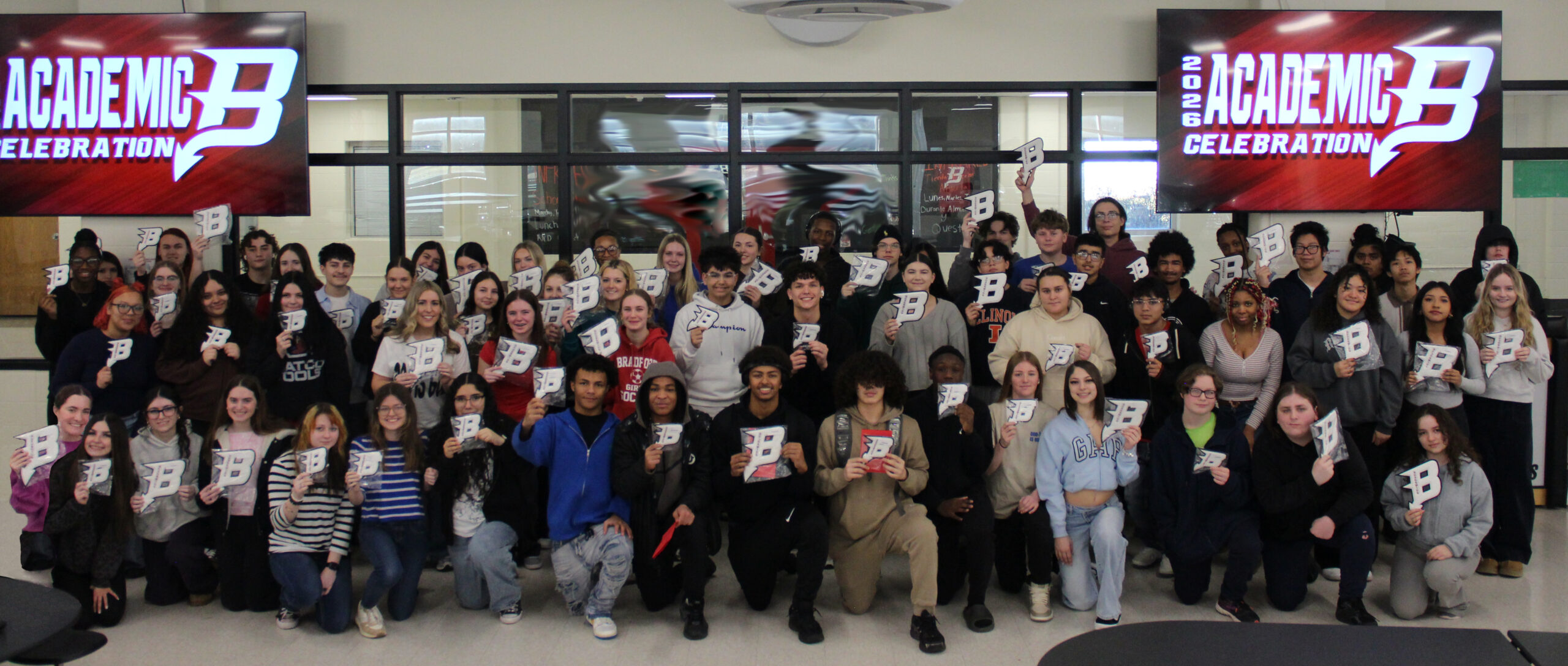 Group photo of student holding Bradford B logos for the academic celebration.