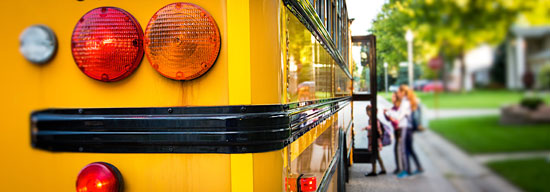 Three students lined up to enter a school bus.