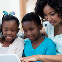 A girl, boy and mother using a laptop.