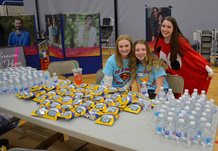 Three girls posing at a snack table featuring pretzels and water bottles.