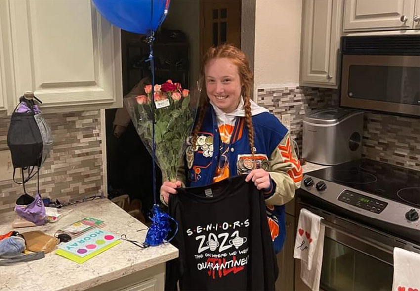 A student from Racine Park displaying her senior shirt, balloons and flowers.