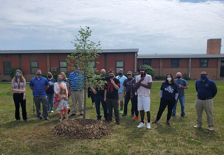 Alexzander Pearson and staff members pose next to the new tree.