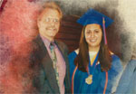 A music teacher standing with a student wearing her graduation cap and gown.