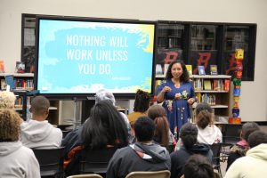 Deanna Singh speaking to students with a presentation slide behind her that reads "nothing will work unless you do."