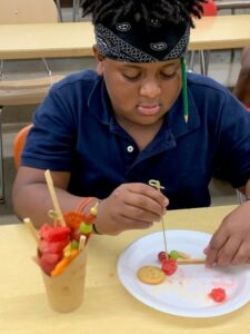 A student wearing a headband works on a charcuterie plate.