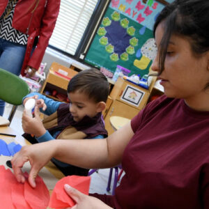 A child and his mother use glue to work on a project.