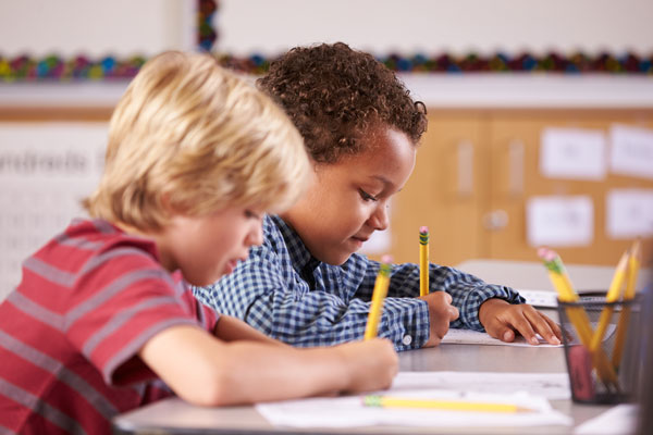 First grade students writing with pencils.