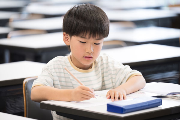 Third grade student writing at a desk.