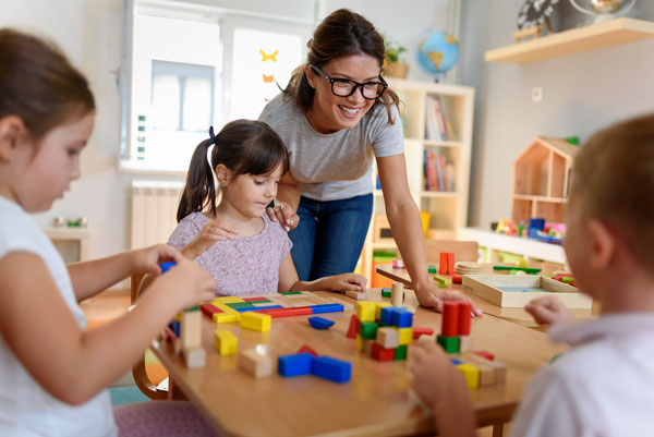 A teacher working with children who are playing with blocks.
