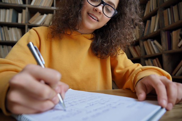 A high school student writing in a notebook.