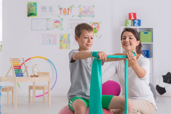 An occupational therapist working with student who is holding stretch bands.