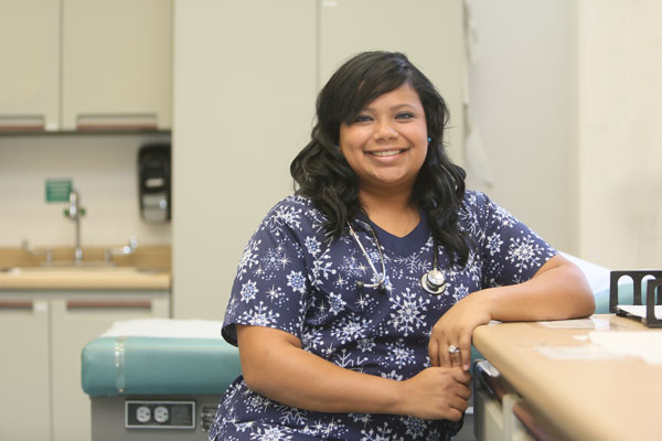 A smiling nurse wearing scrubs and a stethoscope.
