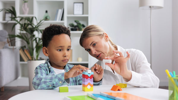 Professional observes small boy playing with puzzle game.