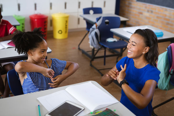 teacher and a girl talking in hand sign language at elementary school