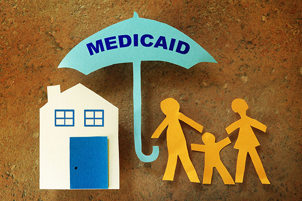 Family holding an umbrella with Medicaid written on it.