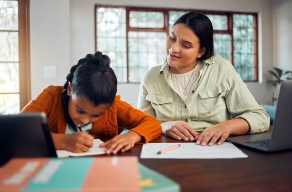 Woman helping girl with school work.