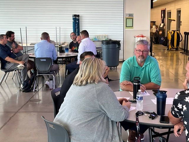 Many people sitting at tables having a conversation.