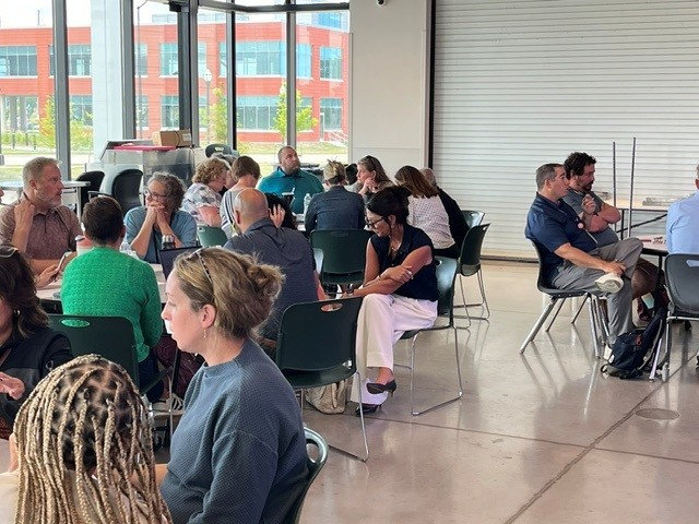 Many people sitting at tables having a conversation.
