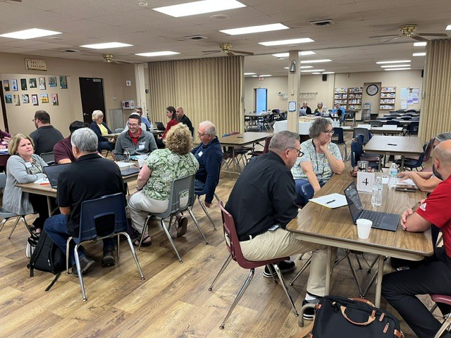 Many people sitting at tables having a conversation.